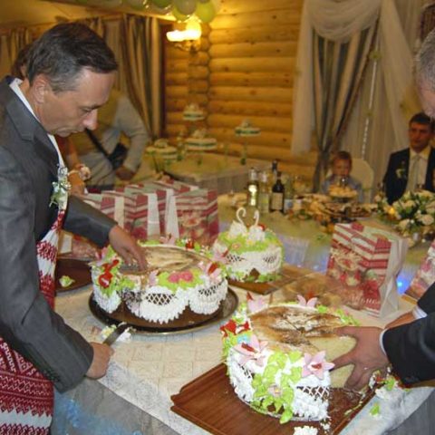 Старости розрізають коровай на весіллі